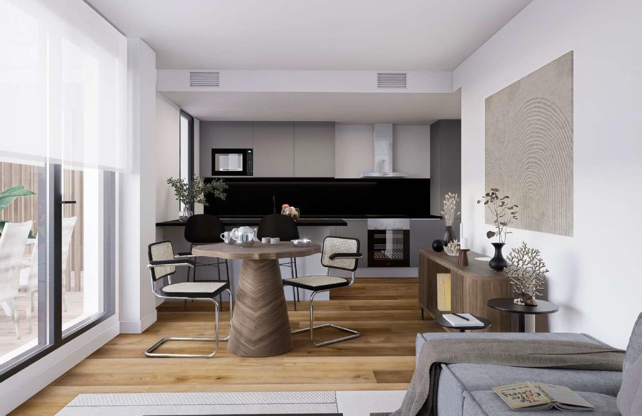 Espace de vie ouvert avec cuisine moderne grise, finitions Porcelanosa et grandes baies vitrées offrant une transition fluide vers la terrasse extérieure.