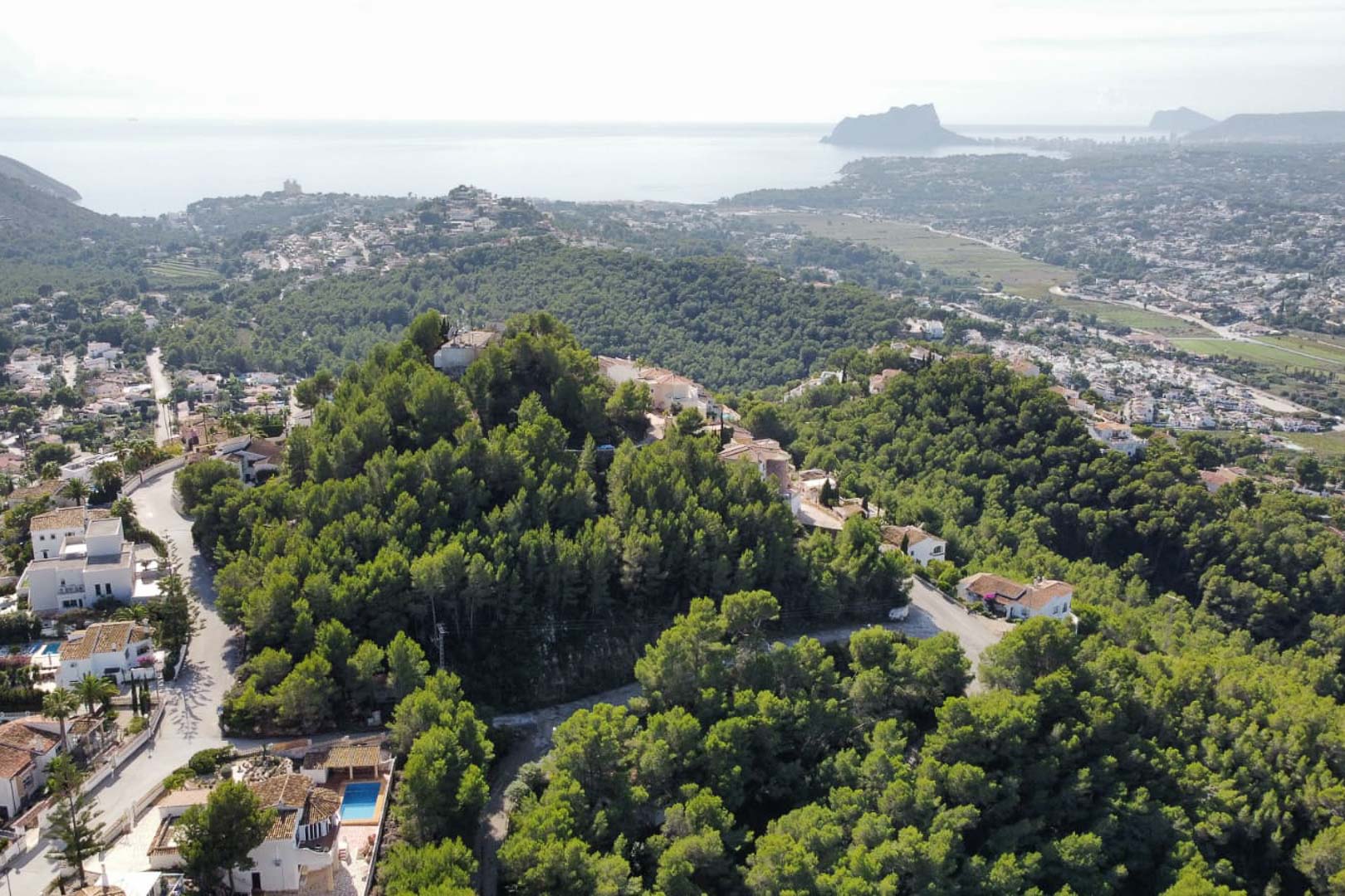 Vue aérienne du quartier résidentiel de Paichi à Moraira, illustrant la forêt de pins et les vues panoramiques sur la mer Méditerranée et le Peñón de Ifach.