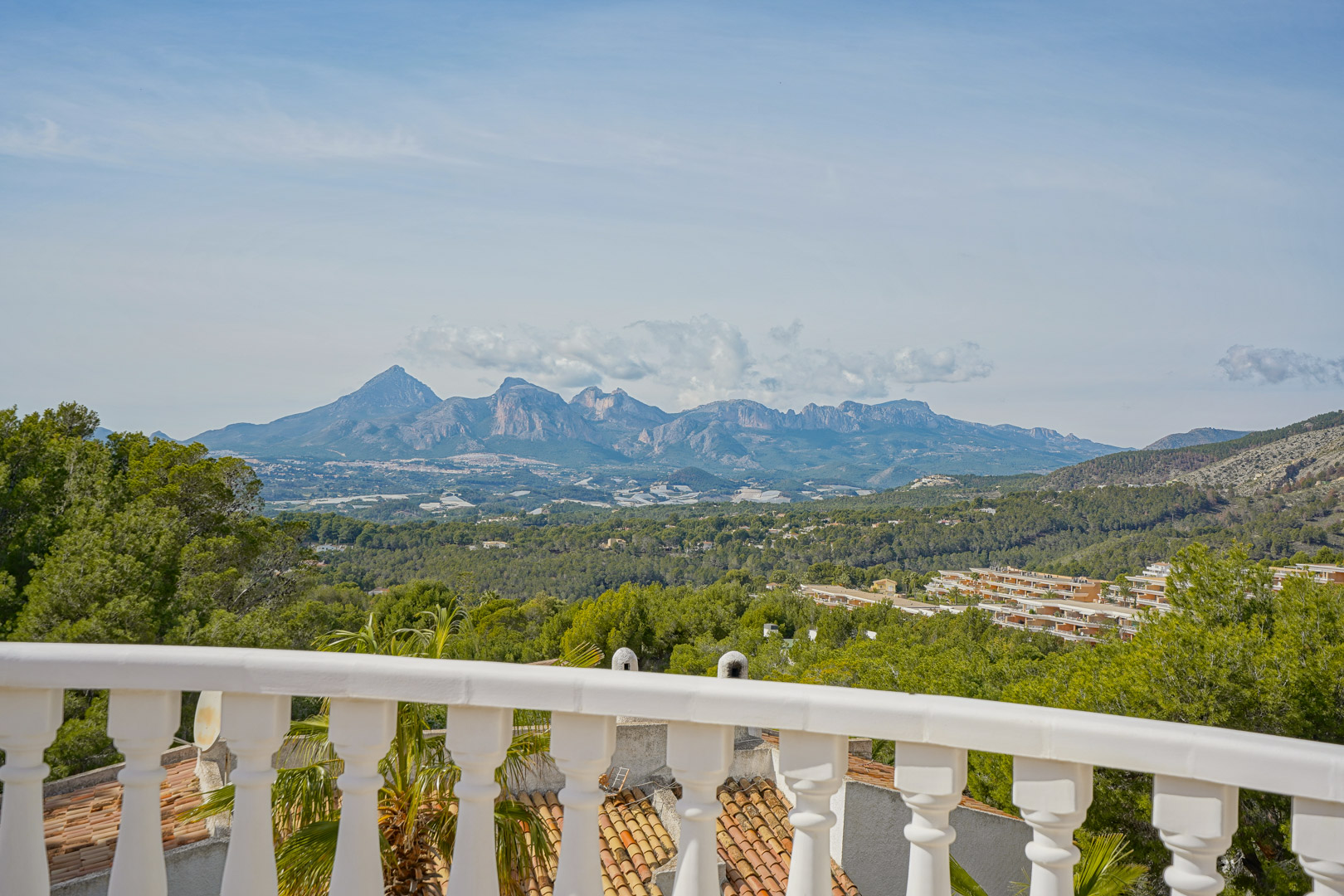 Terrasse avec balustrade blanche classique offrant une vue panoramique sur les massifs du Puig Campana et de la Sierra Aitana.