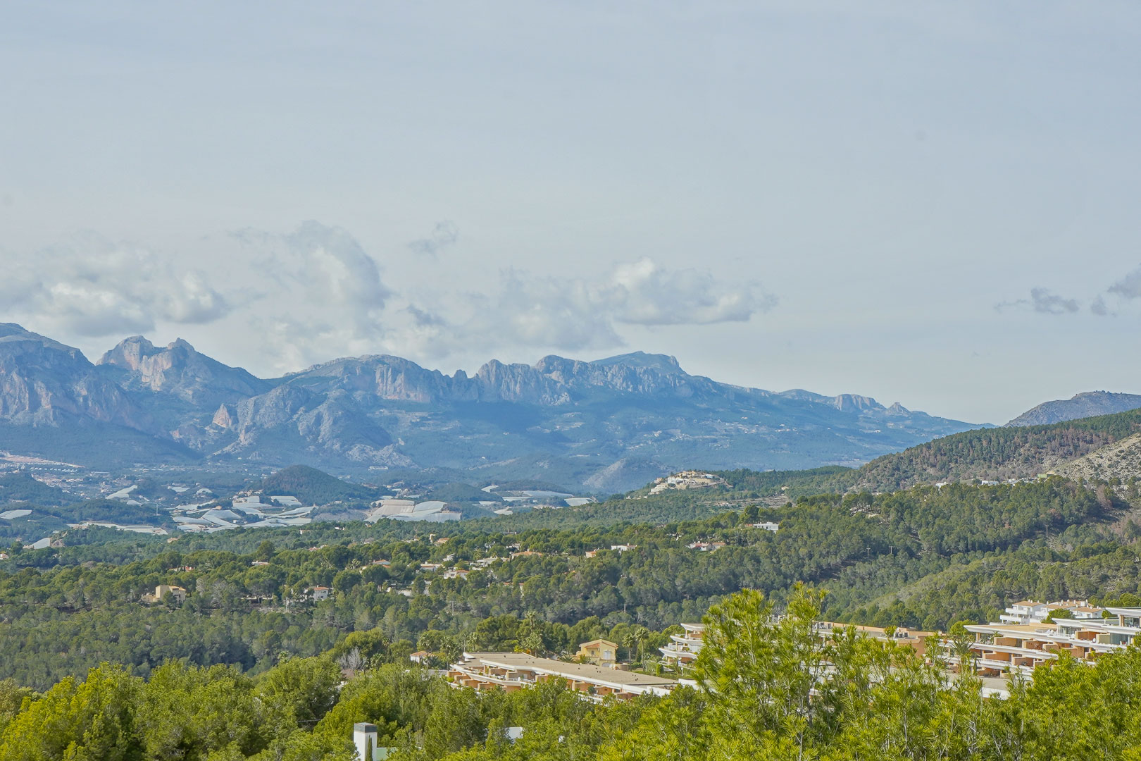 Vues panoramiques sur la chaîne de montagnes de la Marina Baixa, avec les sommets de la Sierra Aitana surplombant une vallée de pins.