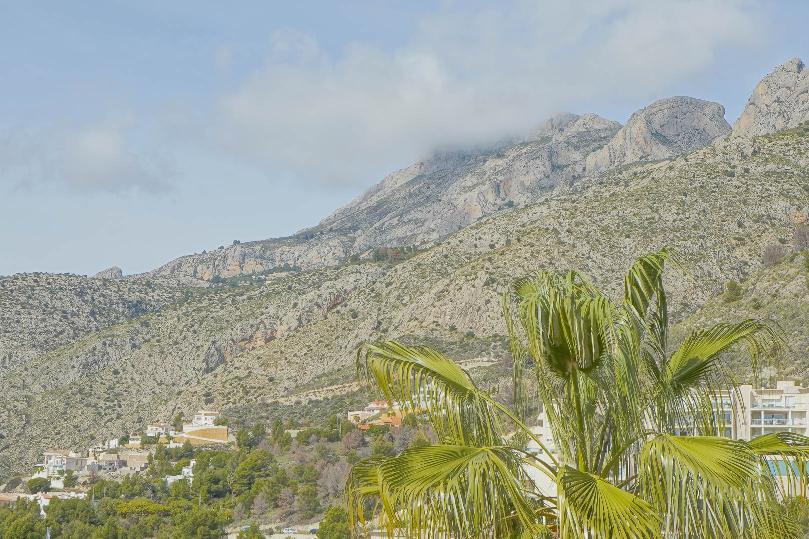 Vues panoramiques sur la chaîne de montagnes Sierra de Bernia, mettant en valeur les sommets rocheux et la végétation locale sous un ciel dégagé.