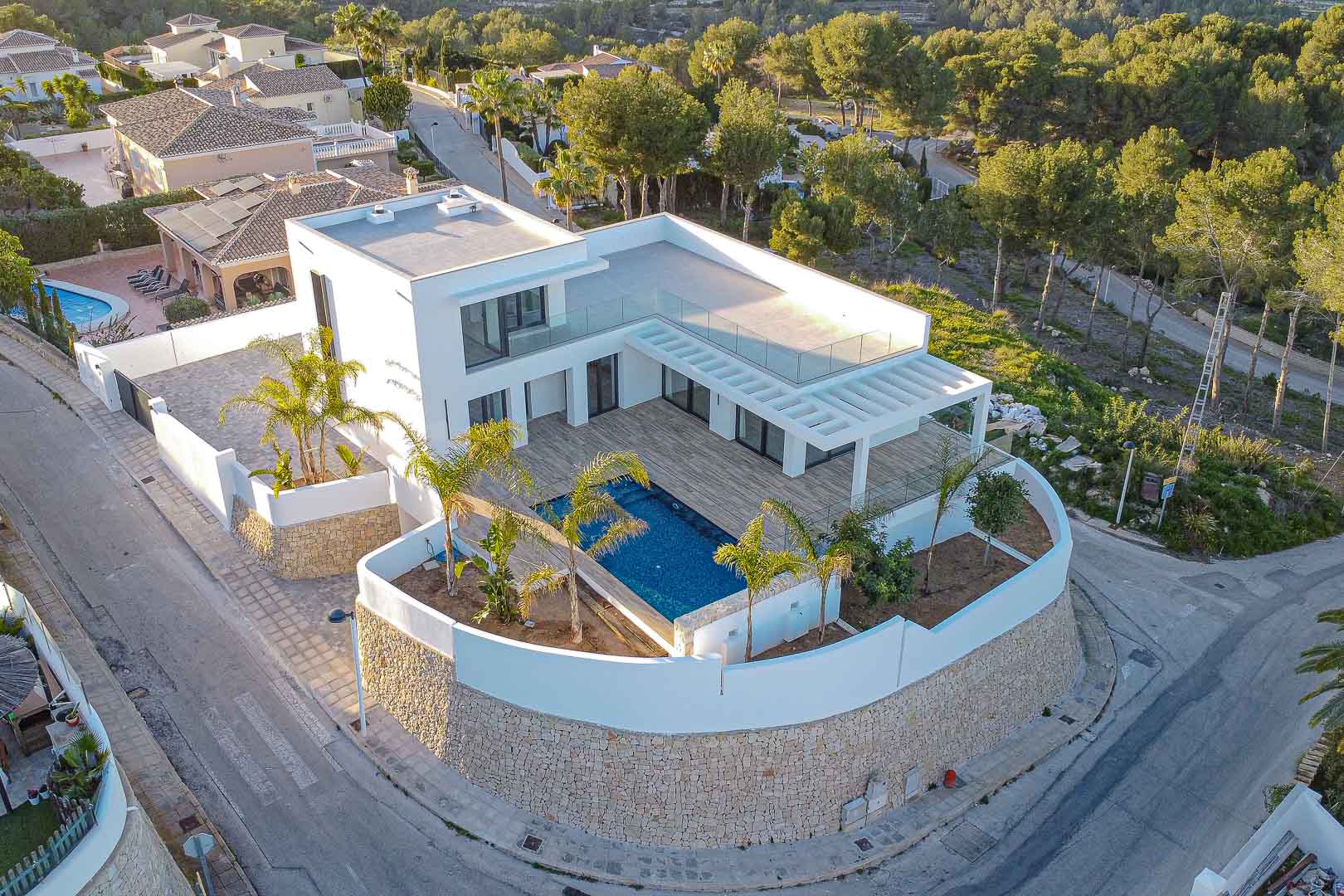 Vue aérienne de la villa moderne avec piscine bleue, terrasse avec pergola et jardin méditerranéen à Benimeit, Moraira.