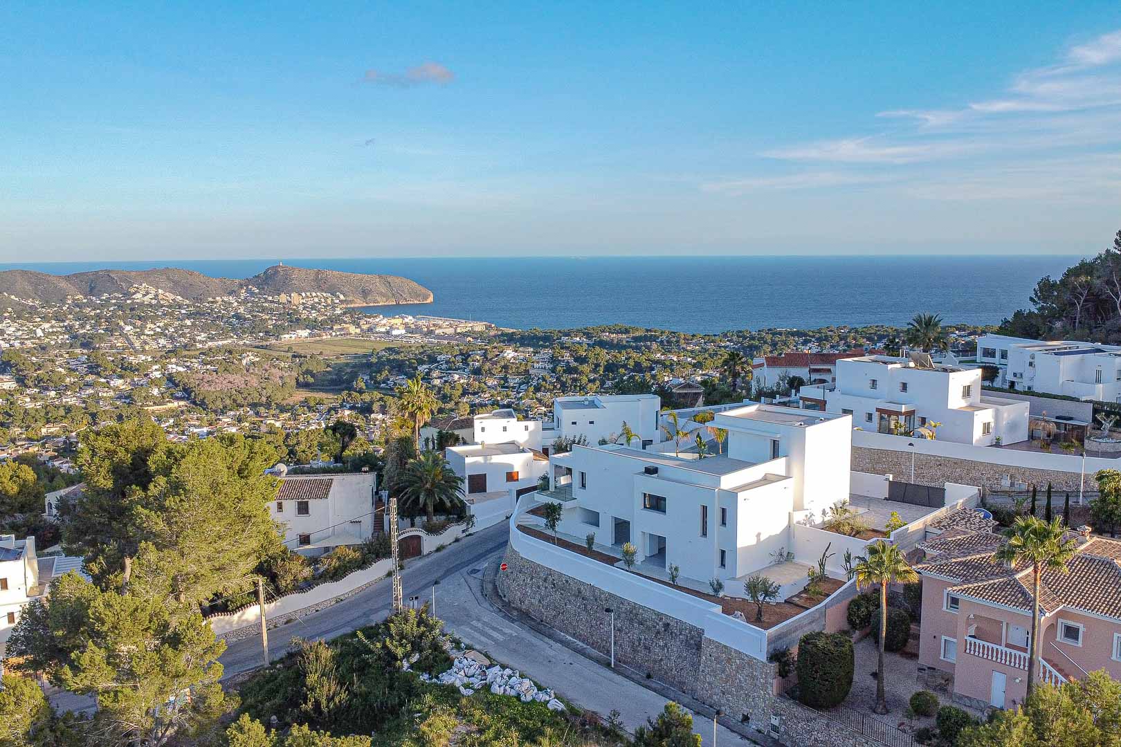 Vue aérienne d'une villa blanche moderne à Benimeit avec vue panoramique sur la mer et le paysage urbain.