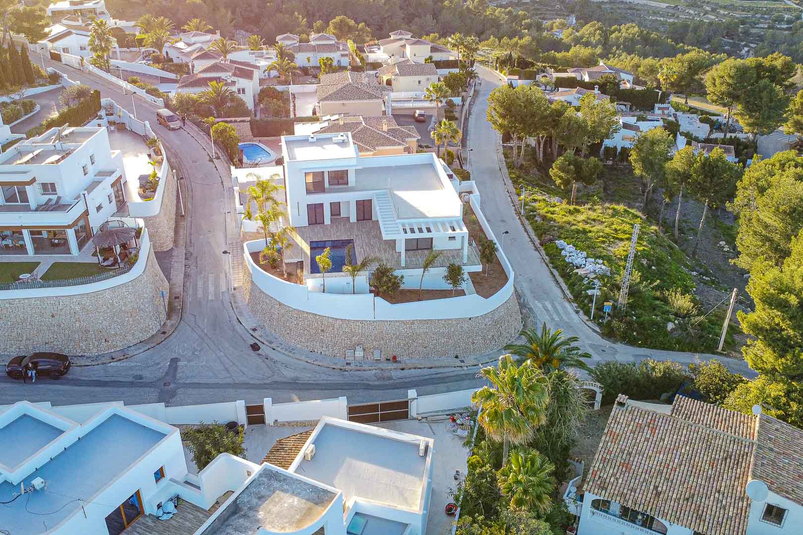 Vue aérienne d'une villa moderne avec piscine, entourée d'un mur de pierre et de jardins à Benimeit, Moraira.