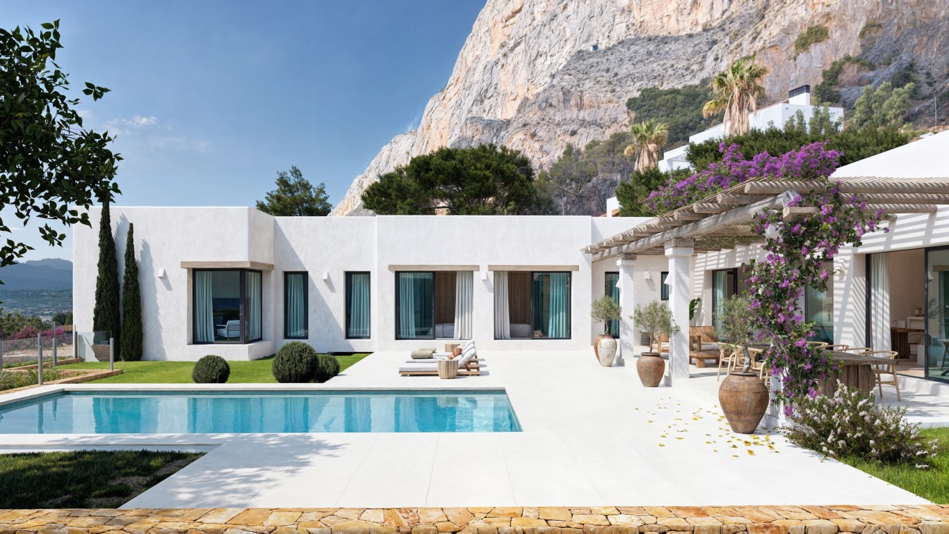 Villa blanche de style méditerranéen avec piscine rectangulaire, terrasse en dalles claires et pergola en bois fleurie au pied des impressionnantes falaises du Montgó.