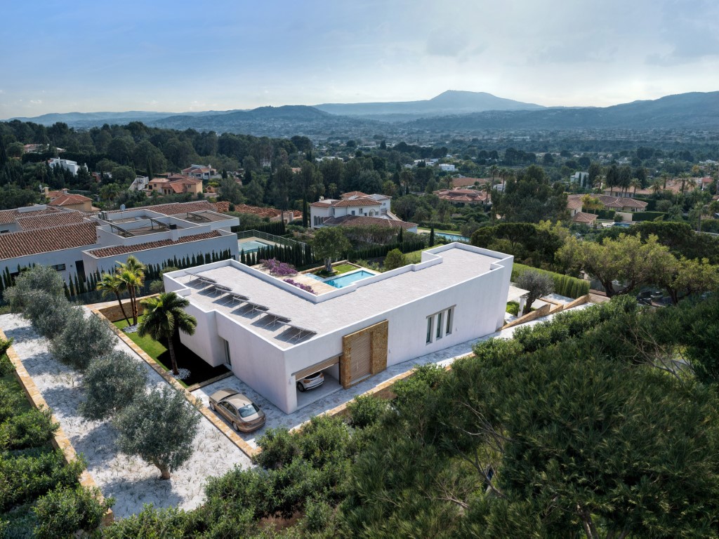 Vue aérienne de la villa contemporaine avec panneaux solaires, garage intégré et jardin paysager surplombant la vallée et les montagnes.
