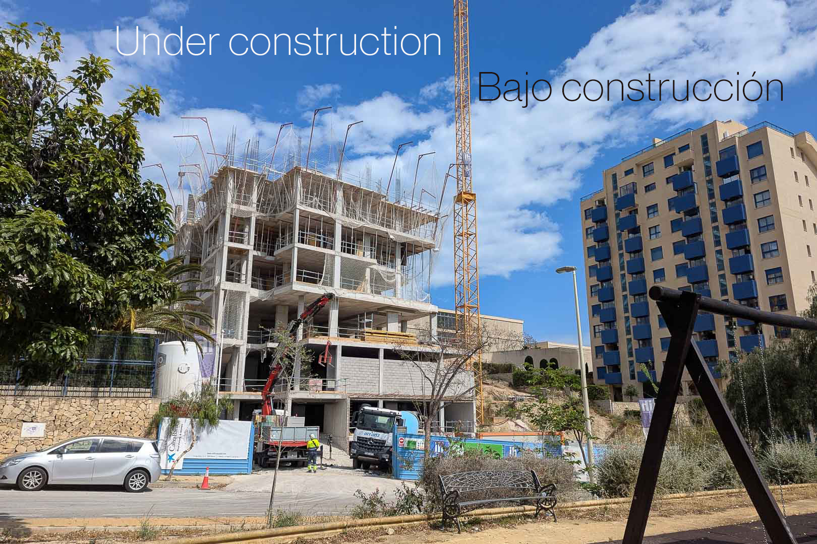 Vue extérieure de la phase initiale de construction à Calpe, montrant la structure en béton, la grue à tour et les engins de chantier sur le site.