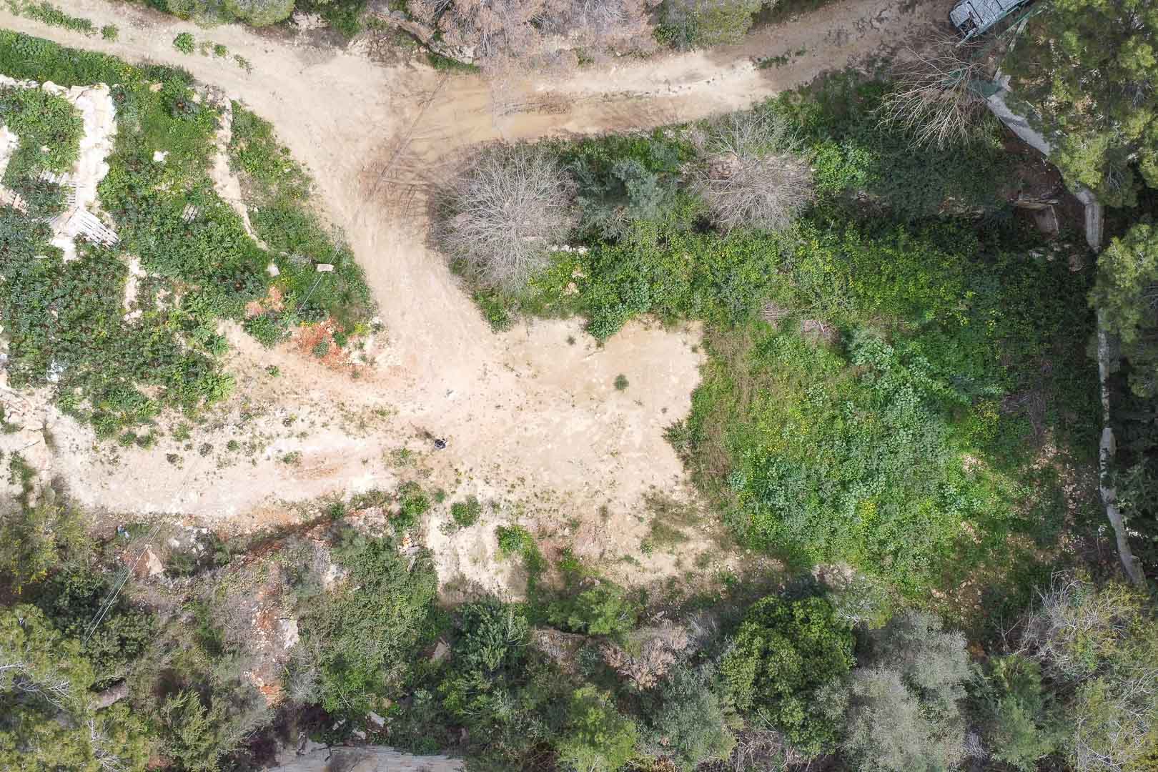 Vue aérienne zénithale du terrain à bâtir, entouré d'une végétation méditerranéenne dense et prêt pour le début des travaux de cette villa personnalisée.