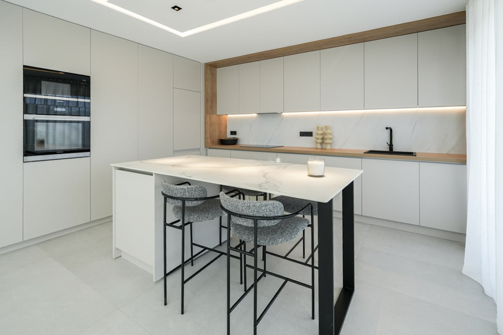 Détail de la cuisine avec îlot en marbre et tabourets gris. Design moderne et fonctionnel.