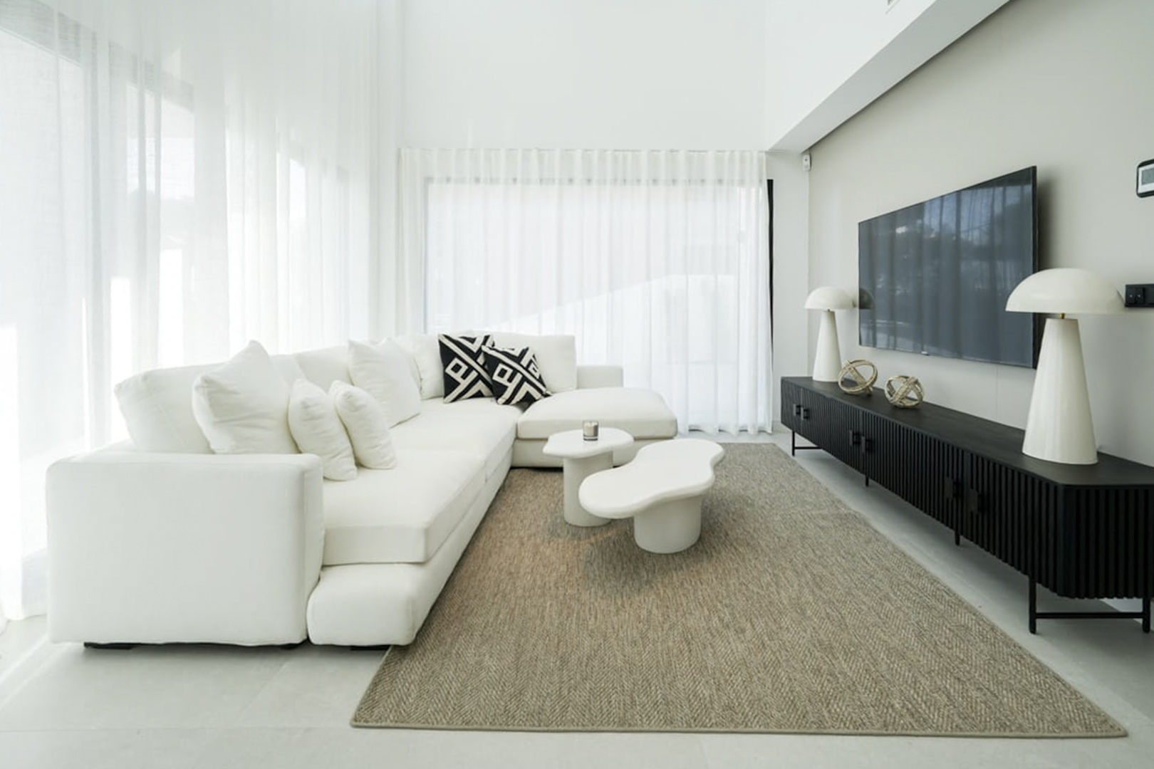 Salon lumineux avec canapé modulable blanc, table d'appoint moderne et tapis en jute.