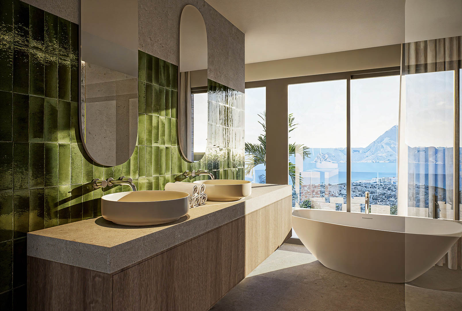 Salle de bain avec double vasque, carrelage mural vert brillant et baignoire îlot offrant une vue imprenable sur la mer à travers de larges baies vitrées.
