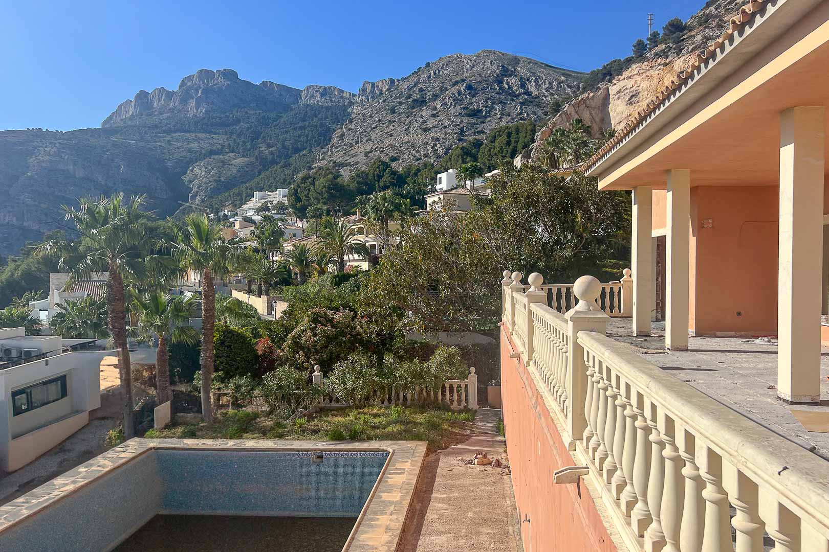 Terrasse avec balustrade classique et vue sur la Sierra de Bernia. L'espace extérieur dispose d'une piscine privée entourée de palmiers et de verdure.