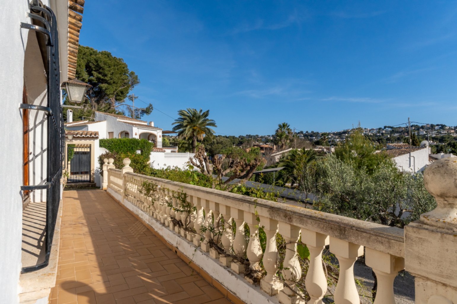Terrasse extérieure avec sol en terre cuite et balustrade classique, offrant une vue dégagée sur le quartier résidentiel de Cap Martí à Jávea.