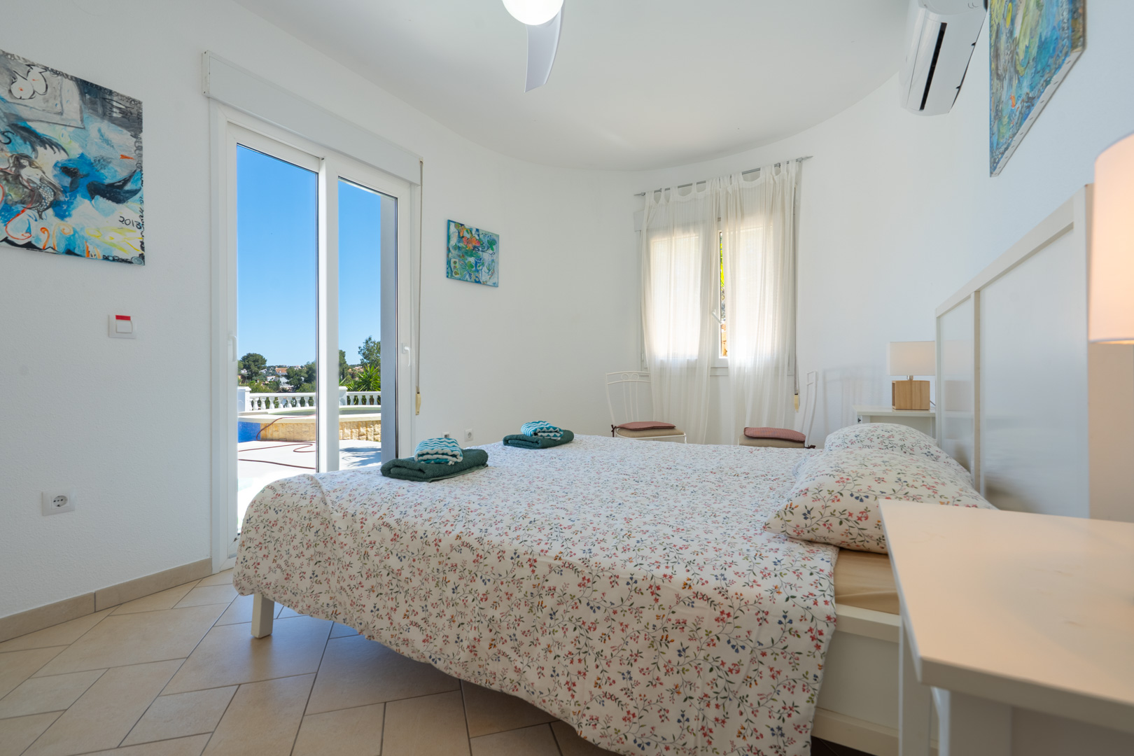 Chambre lumineuse avec accès direct à la terrasse et à la piscine, équipée de la climatisation, de sols en grès et de menuiseries en PVC.