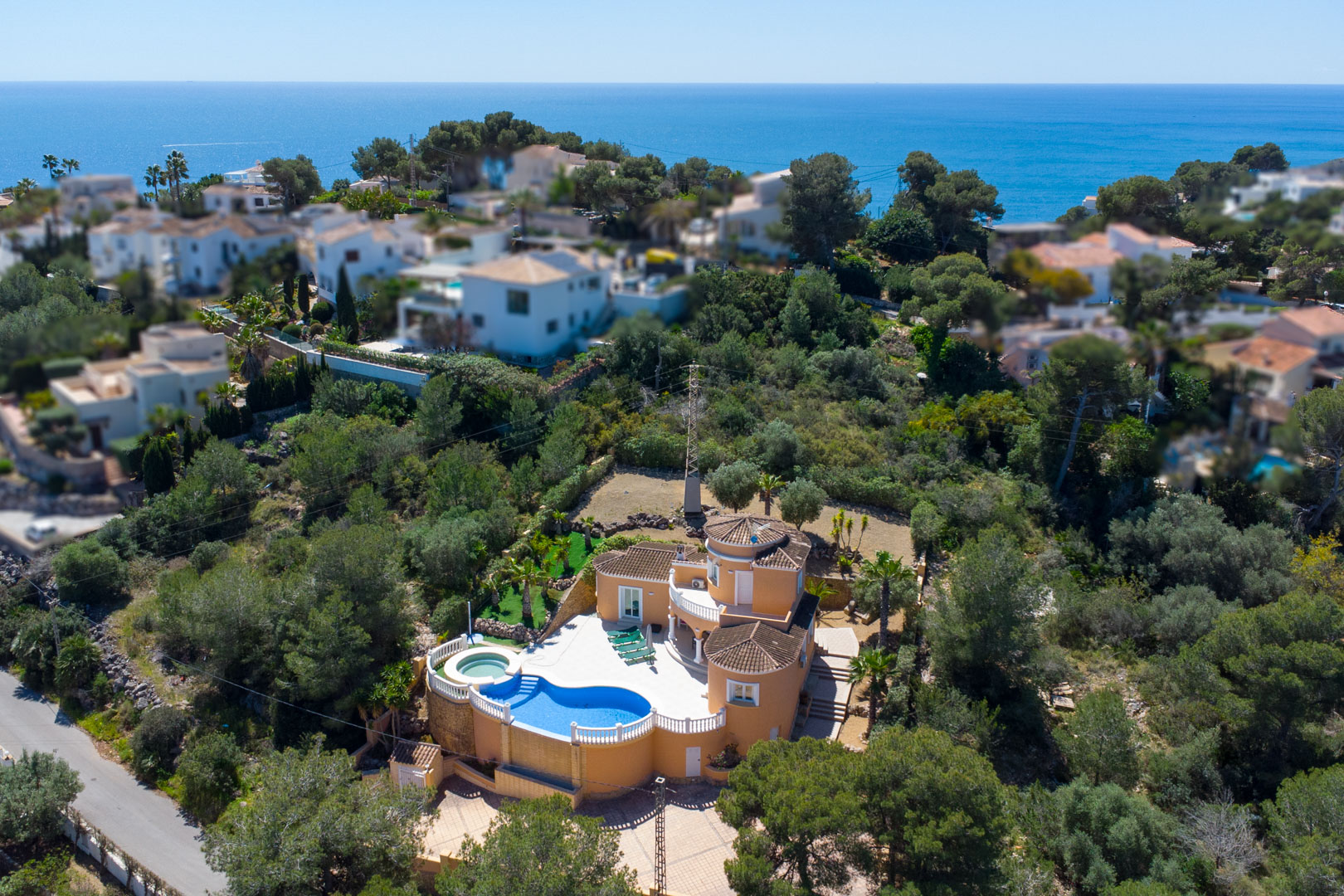 Vue aérienne de la villa aux tons ocre, avec sa piscine de forme libre, ses balustrades blanches et une terrasse offrant une vue dégagée sur la mer Méditerranée.