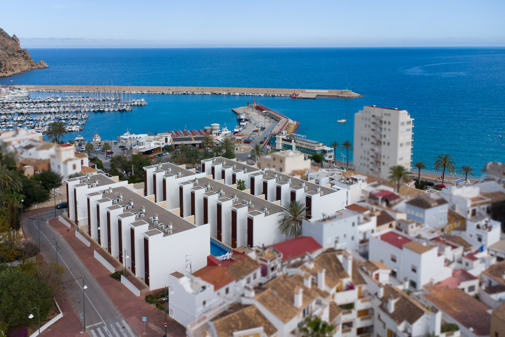Vue aérienne du port de Jávea et des complexes résidentiels modernes au bord de la Méditerranée, soulignant la proximité immédiate de la côte.