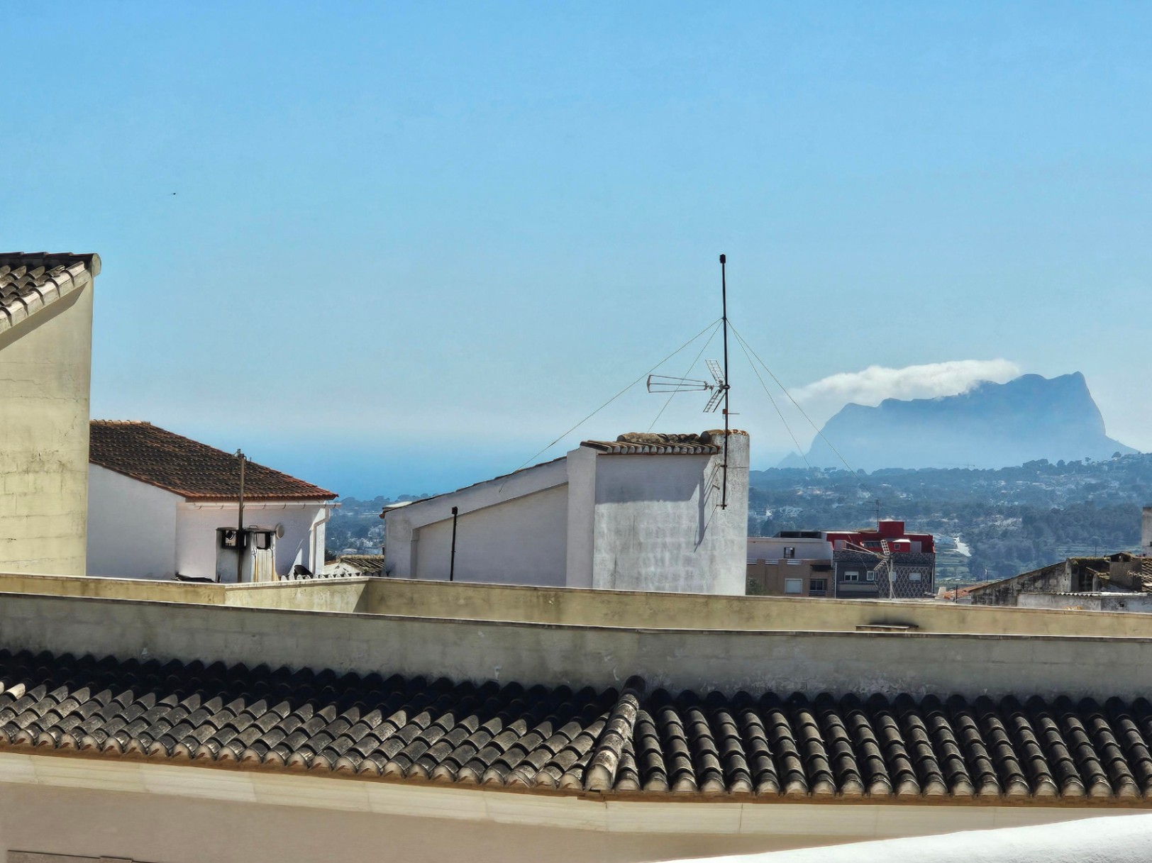 Vues panoramiques depuis la terrasse supérieure sur les toits du village, la mer Méditerranée et la silhouette du Peñón de Ifach à l'horizon.