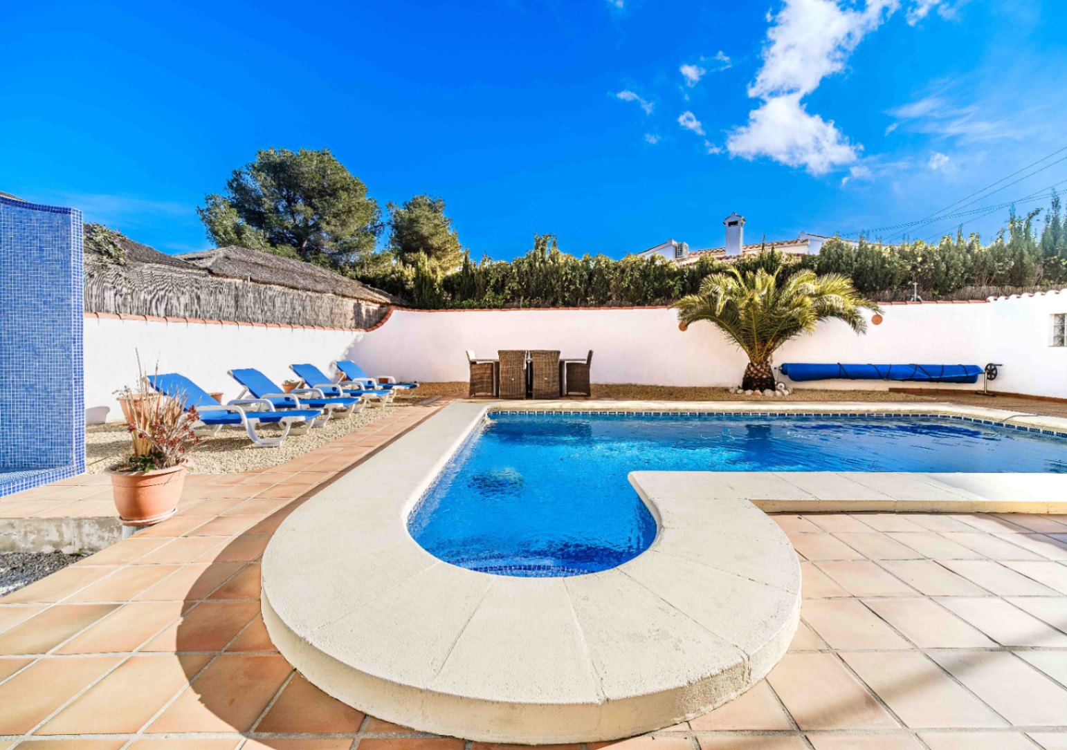Piscine au sel avec escalier roman, terrasse en grès et espace de bronzage. L'aménagement comprend un coin repas extérieur, un palmier et une douche en mosaïque bleue.