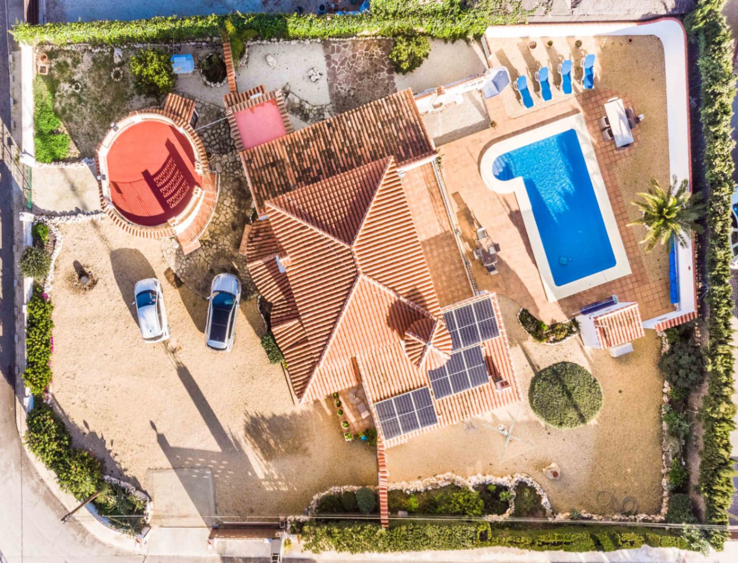 Vue aérienne de la villa révélant les panneaux solaires, la piscine avec terrasse bien exposée et l'aménagement du terrain avec parking privé.