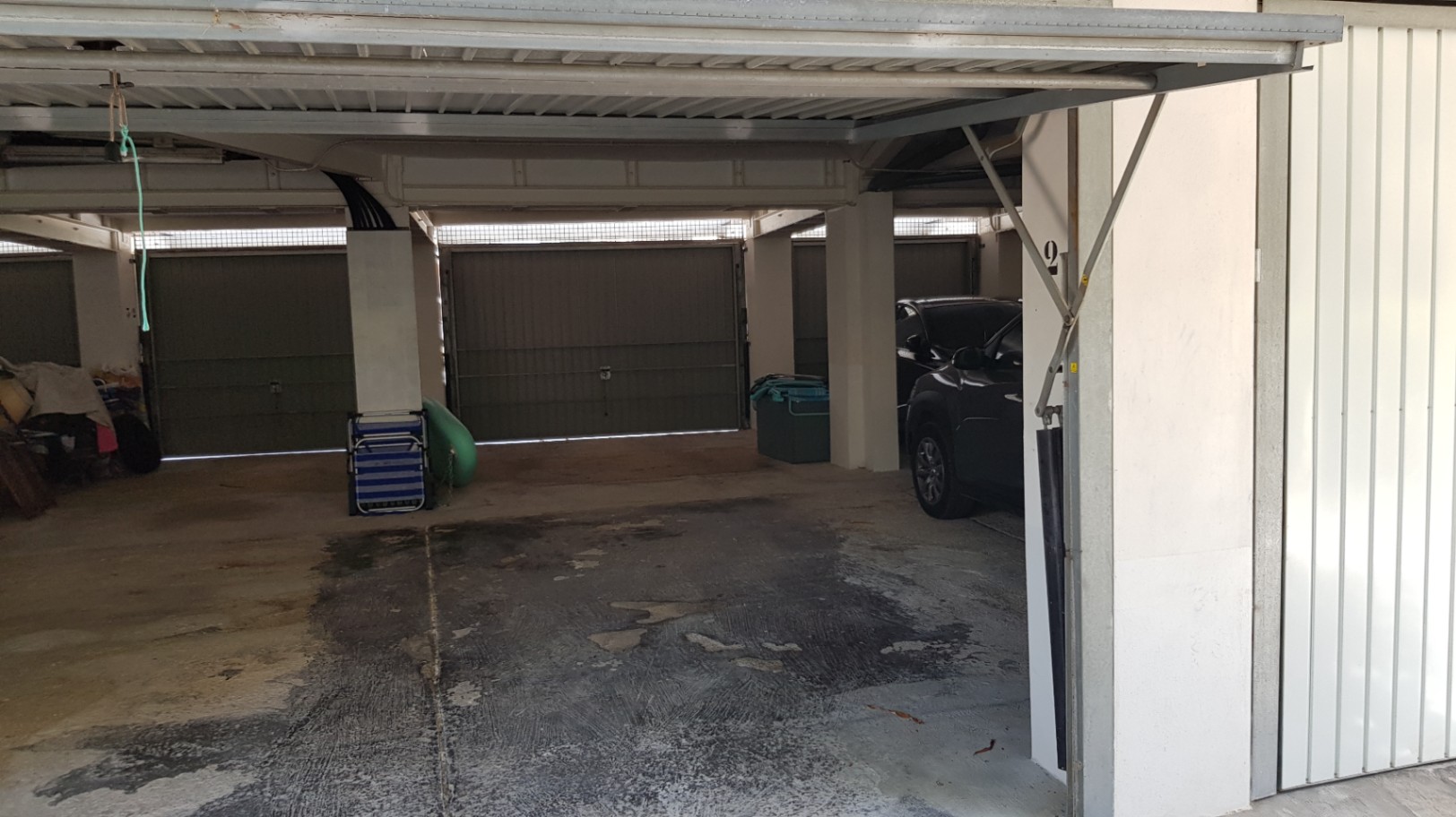 Garage privé couvert avec sol en béton et portes métalliques basculantes, offrant un stationnement sécurisé et protégé au sein de la résidence.