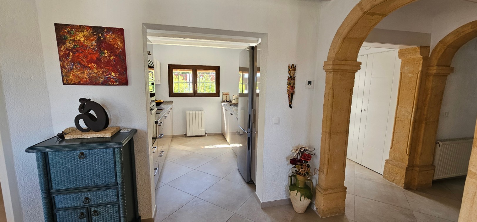 Hall d'entrée avec arches en pierre de Tosca menant à une cuisine indépendante lumineuse, équipée de radiateurs et d'un sol en céramique.