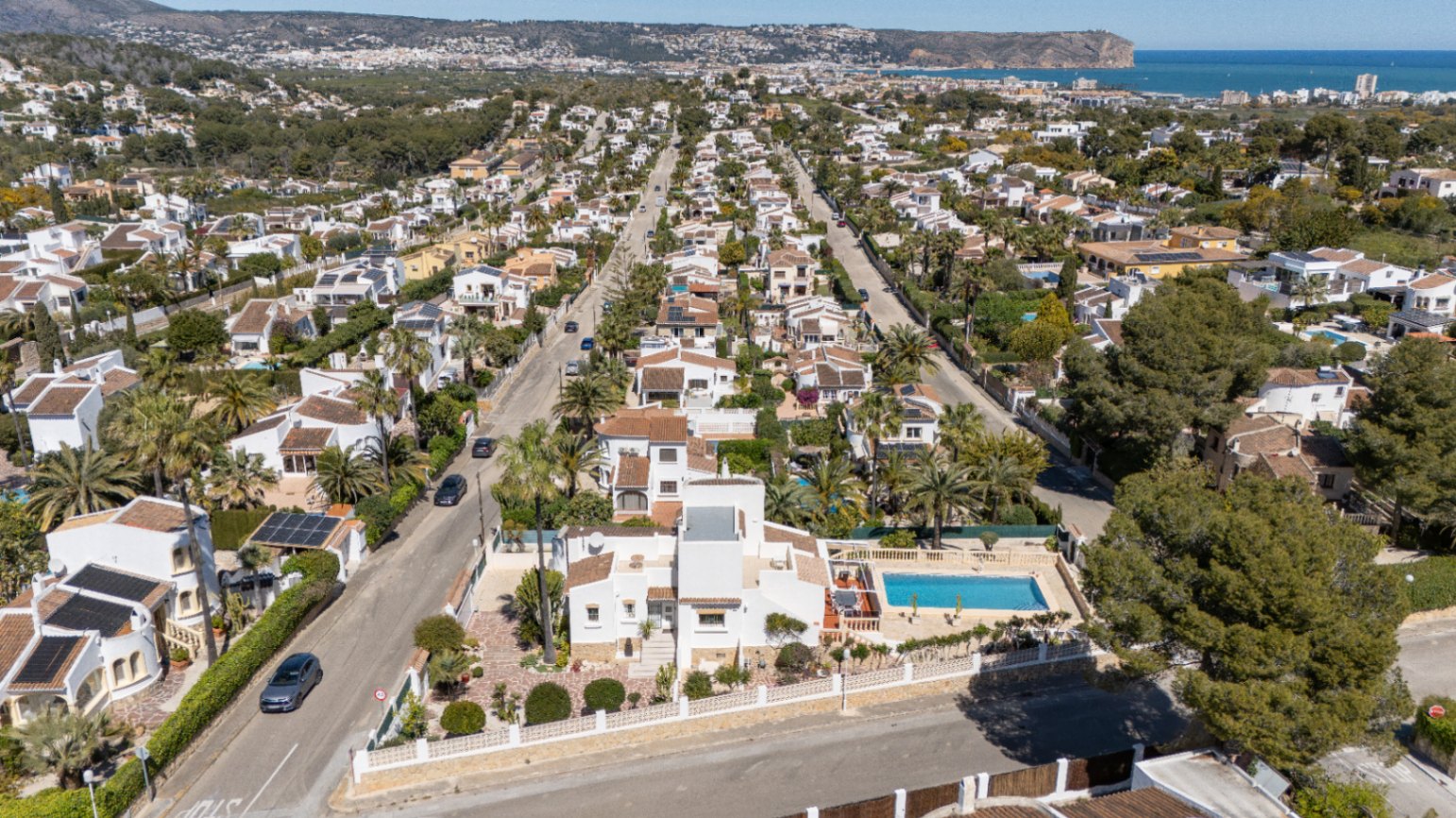Vue aérienne de la propriété à Pinosol, mettant en valeur sa façade blanche, sa piscine privée et la proximité de la mer Méditerranée à l'horizon.