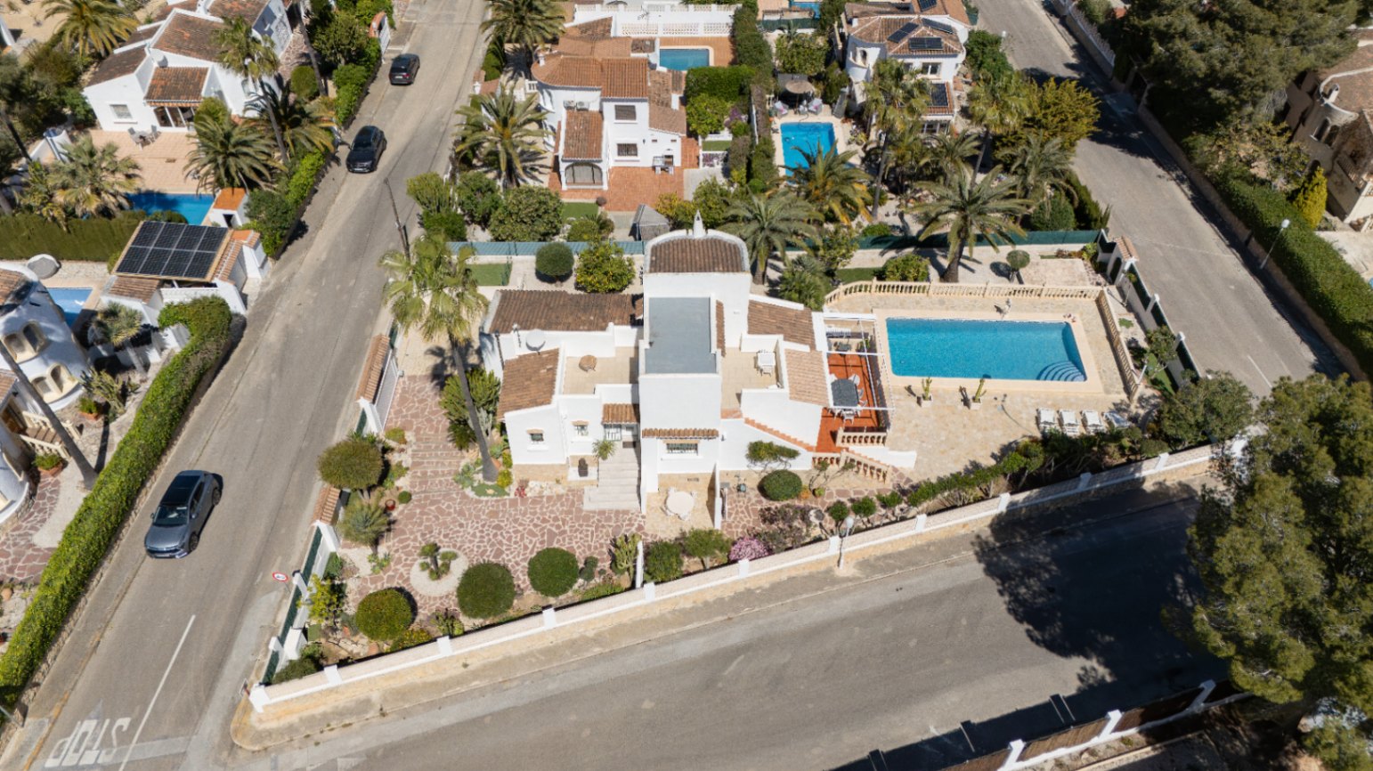 Vue aérienne de la villa sur un terrain d'angle, avec sa piscine privée, ses vastes terrasses pavées et son jardin méditerranéen soigné à Pinosol.