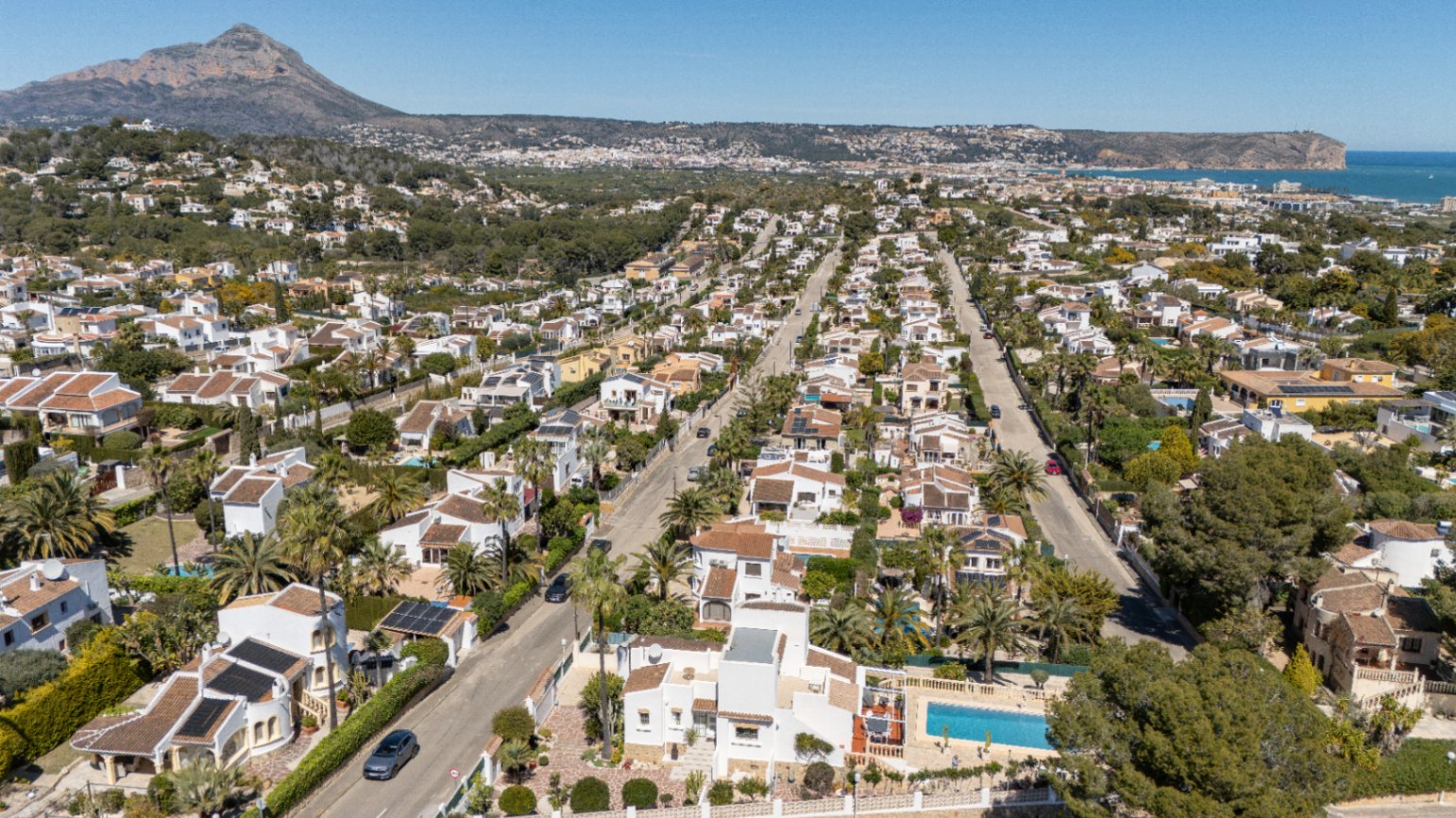 Vue aérienne panoramique du quartier de Pinosol à Jávea, illustrant la proximité entre le massif du Montgó et la mer Méditerranée à l'horizon.