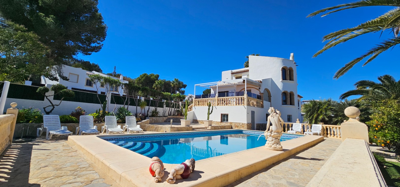 Vue extérieure de la villa avec sa piscine privée, sa terrasse en pierre naturelle et son architecture méditerranéenne aux fenêtres cintrées.