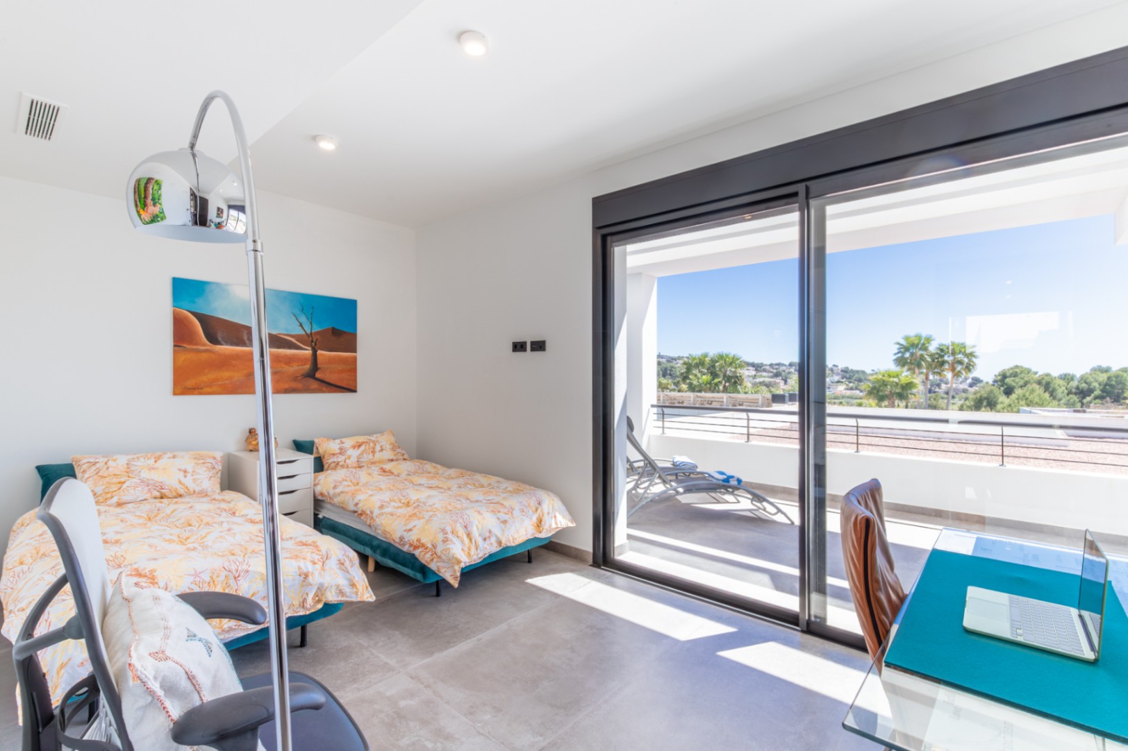 Chambre avec deux lits simples, un coin bureau et un accès direct à une terrasse privée offrant une vue dégagée grâce aux grandes baies vitrées.