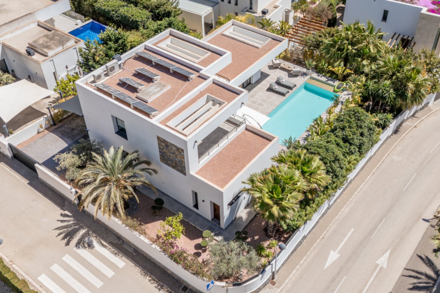 Vue aérienne de la villa moderne avec panneaux solaires sur le toit, piscine privée et jardin méditerranéen arboré offrant une intimité totale sur un terrain d'angle.