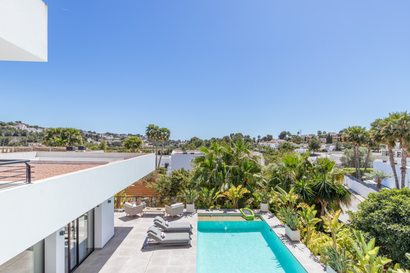 Vue surélevée de l'espace extérieur avec piscine rectangulaire, terrasse en grès cérame et jardin méditerranéen arboré offrant une intimité totale.