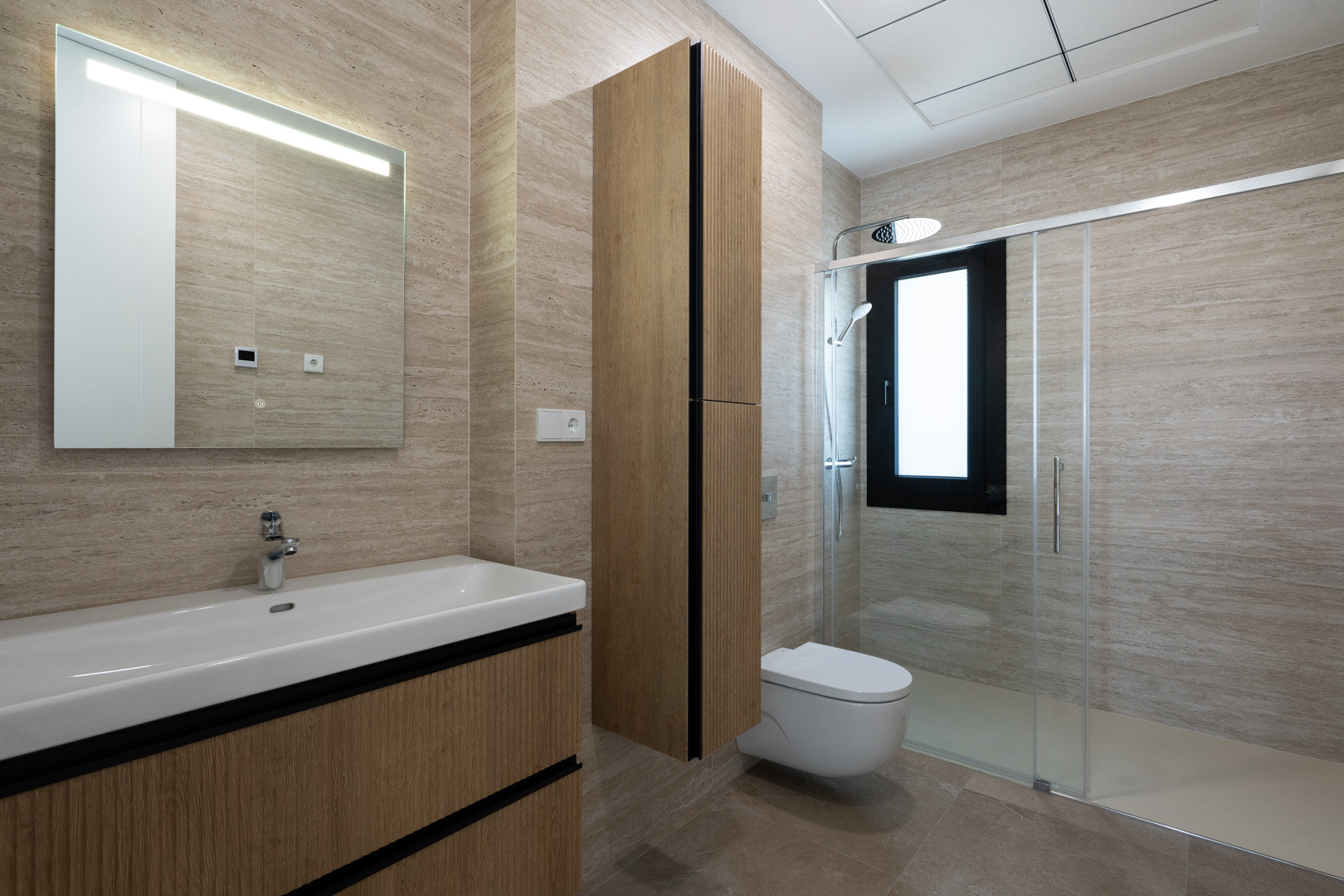 Salle de bain moderne avec carrelage en grès cérame texturé, meuble vasque suspendu en bois, WC suspendu et douche à l'italienne avec paroi vitrée.