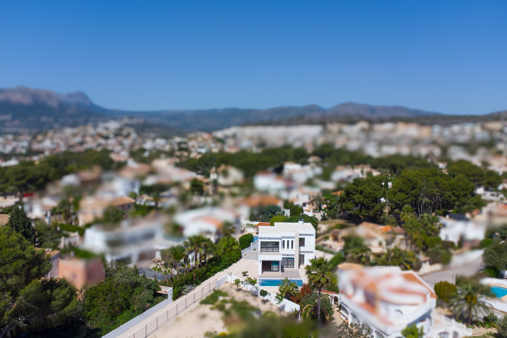 Vue aérienne de la villa contemporaine à deux niveaux avec façade blanche et piscine, illustrant son intégration dans le paysage résidentiel de Benissa.