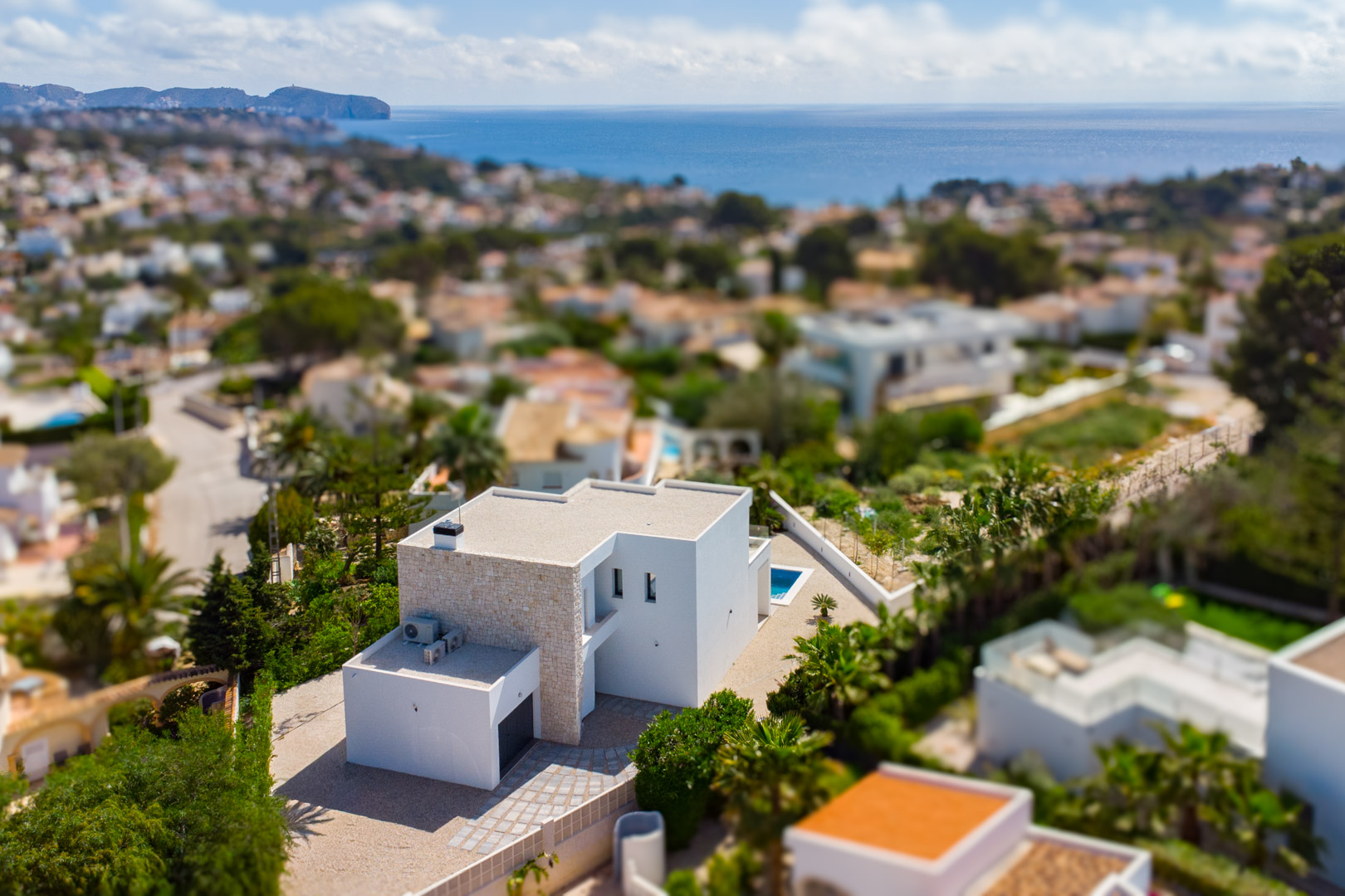 Vue aérienne de la villa moderne aux lignes épurées et façade en pierre naturelle, offrant un panorama sur la mer Méditerranée et le quartier résidentiel.