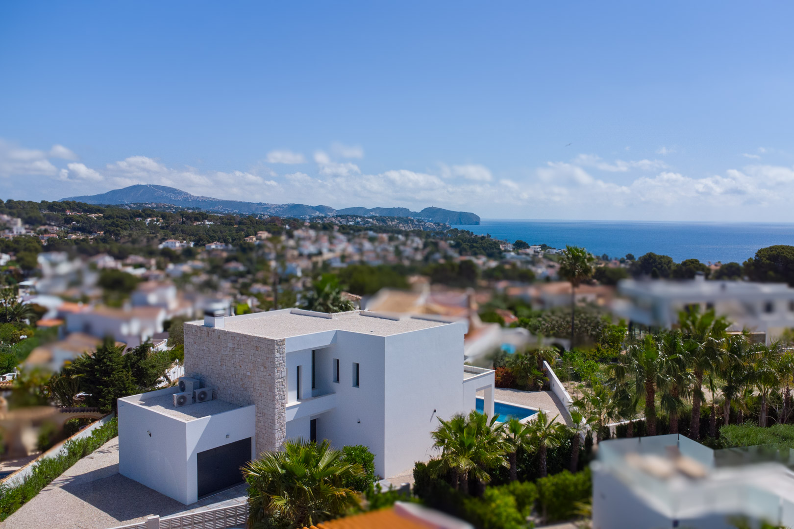 Vue aérienne de la villa moderne avec façade en pierre naturelle, piscine privée et vue dégagée sur la mer Méditerranée à Benissa.