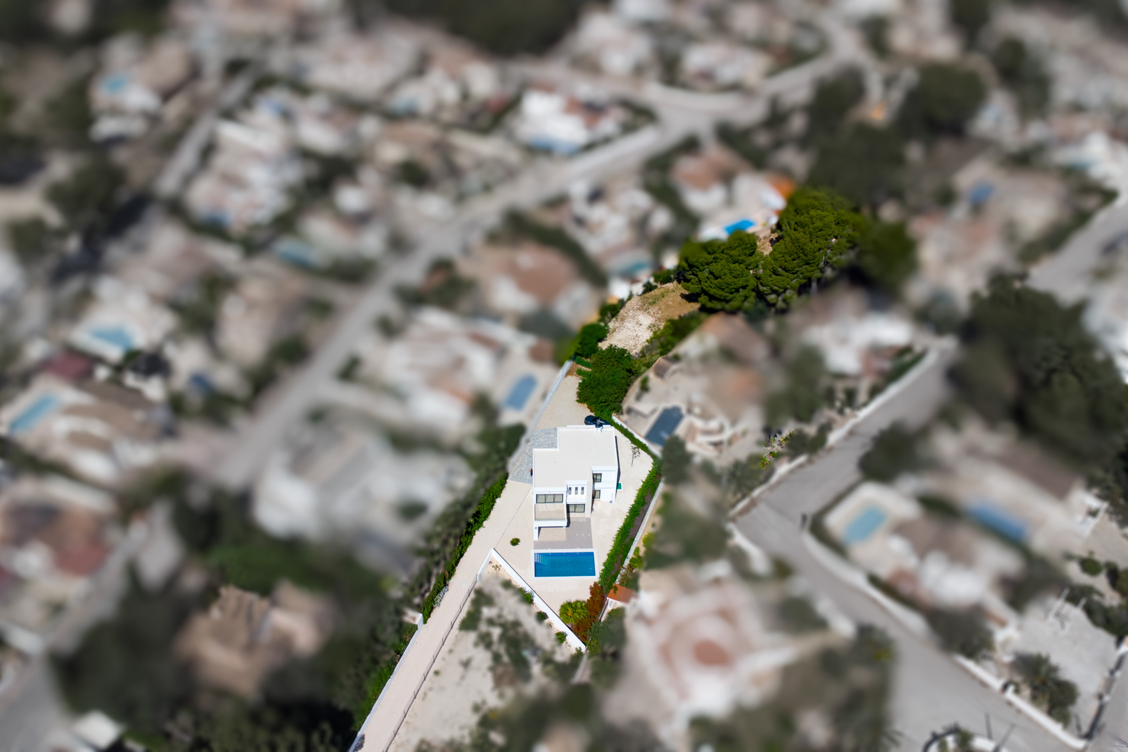 Vue aérienne de la villa moderne sur son vaste terrain plat, illustrant la piscine rectangulaire et la grande zone de jardin privative à La Fustera.