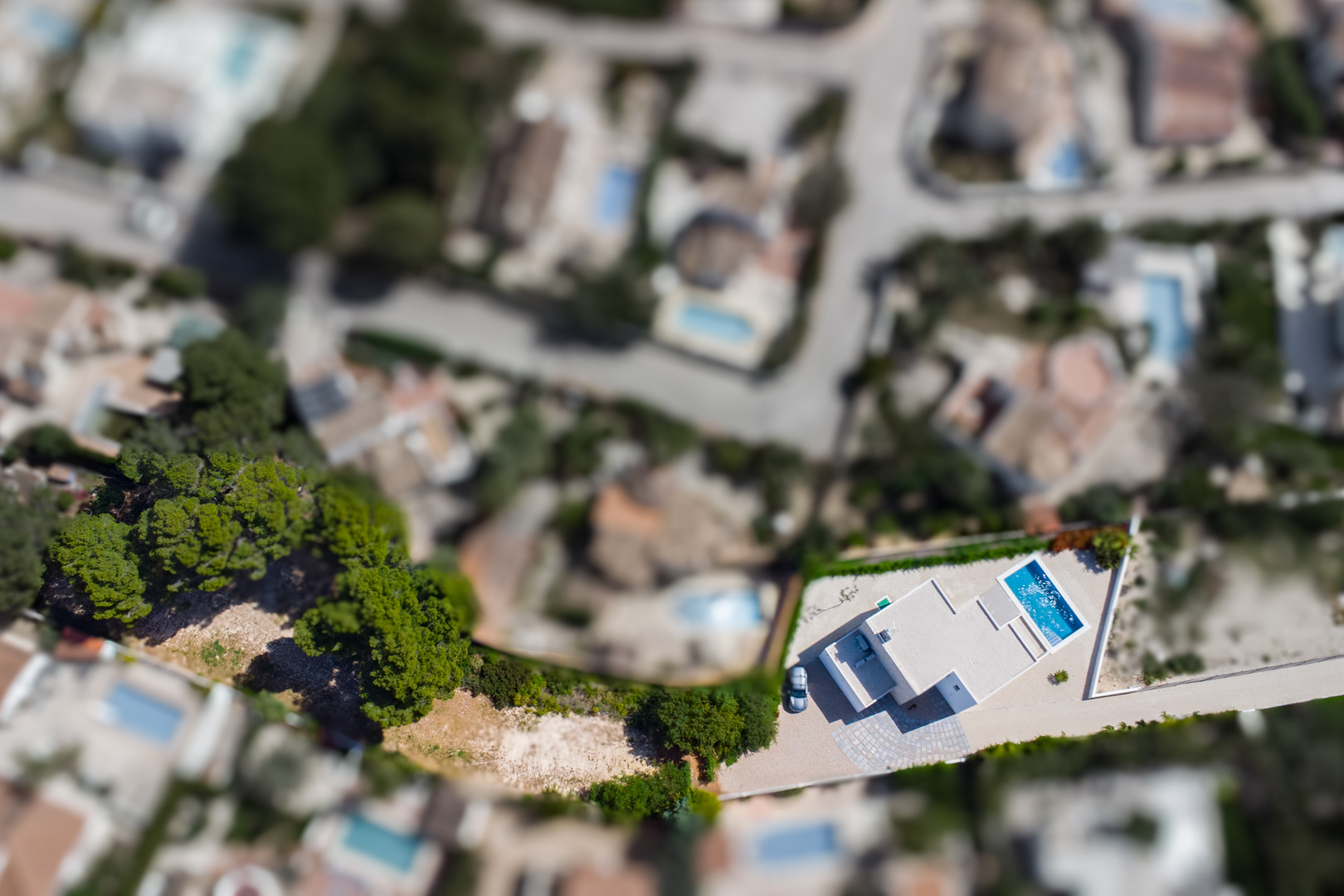 Vue aérienne zénithale de la villa moderne sur son vaste terrain plat, mettant en évidence la piscine rectangulaire et l'aménagement extérieur soigné à La Fustera.