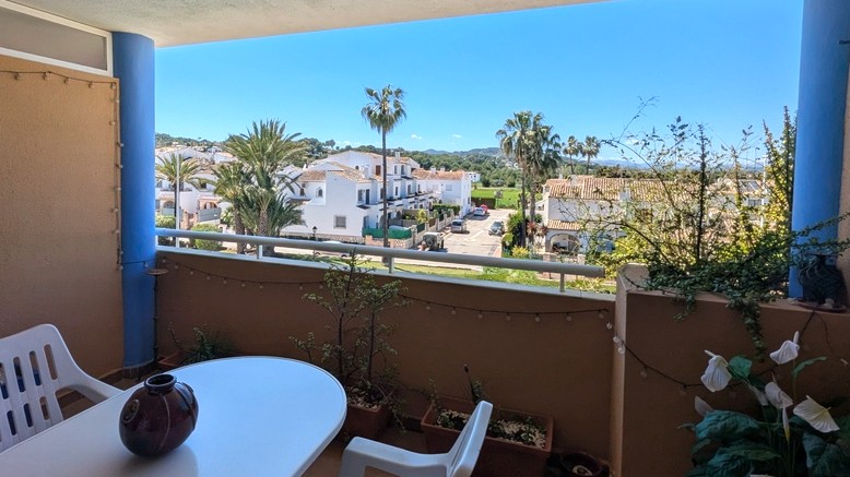 Terrasse couverte avec espace repas offrant une vue dégagée sur les villas méditerranéennes, les palmiers et le mont Montgó.