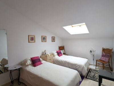 Chambre double lumineuse sous les combles avec un puits de lumière, apportant une clarté naturelle. Elle comprend deux lits simples et un sol carrelé.