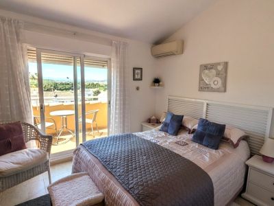 La chambre principale dispose d'un lit double avec tête de lit à lattes, d'une climatisation et d'un accès à une terrasse privée avec vue sur le paysage lointain.