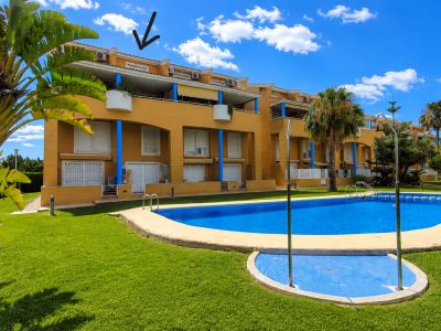 L'immeuble jaune de la communauté, avec piliers bleus, volets blancs et balcons, donne sur la grande piscine communautaire et les jardins entretenus. Le duplex est au dernier étage.
