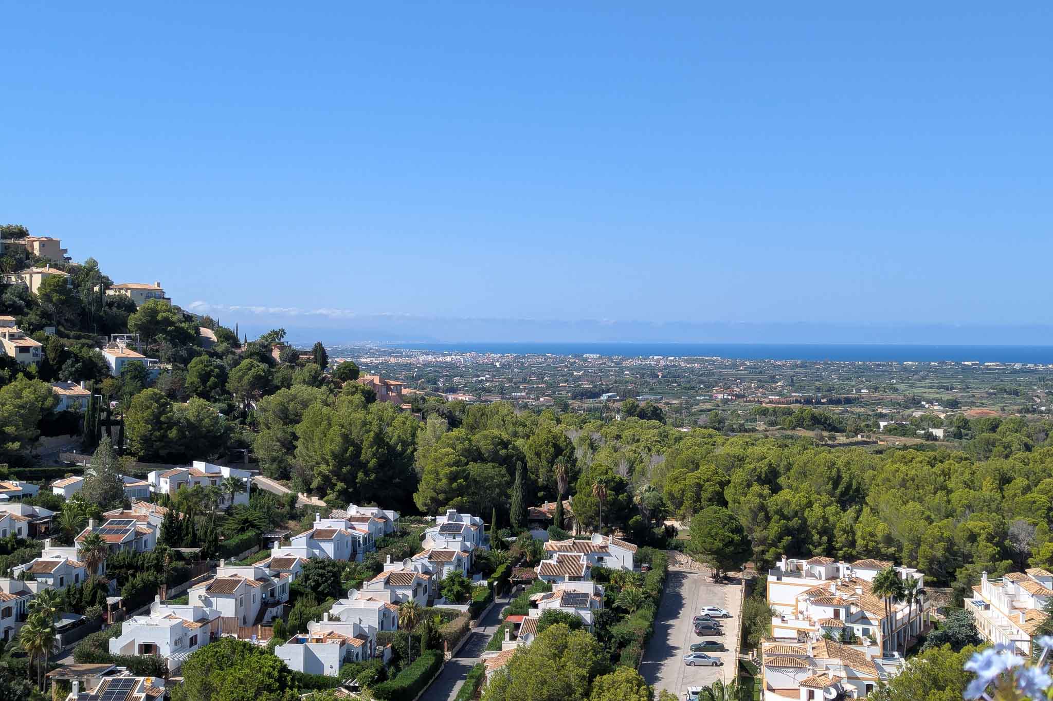 Vues panoramiques depuis La Sella vers la côte, illustrant l'harmonie entre les résidences blanches, la forêt de pins méditerranéenne et l'horizon marin dégagé.
