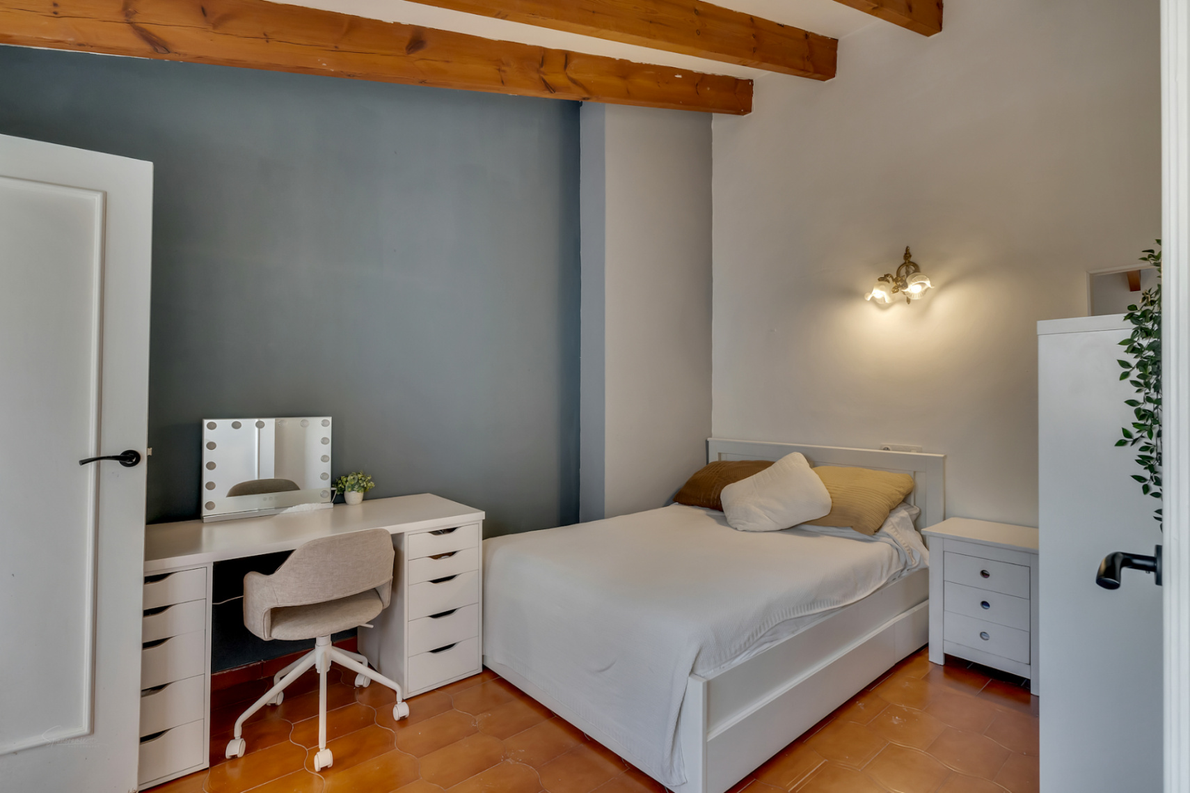 Chambre avec bureau de toilette blanc et lit avec literie blanche.