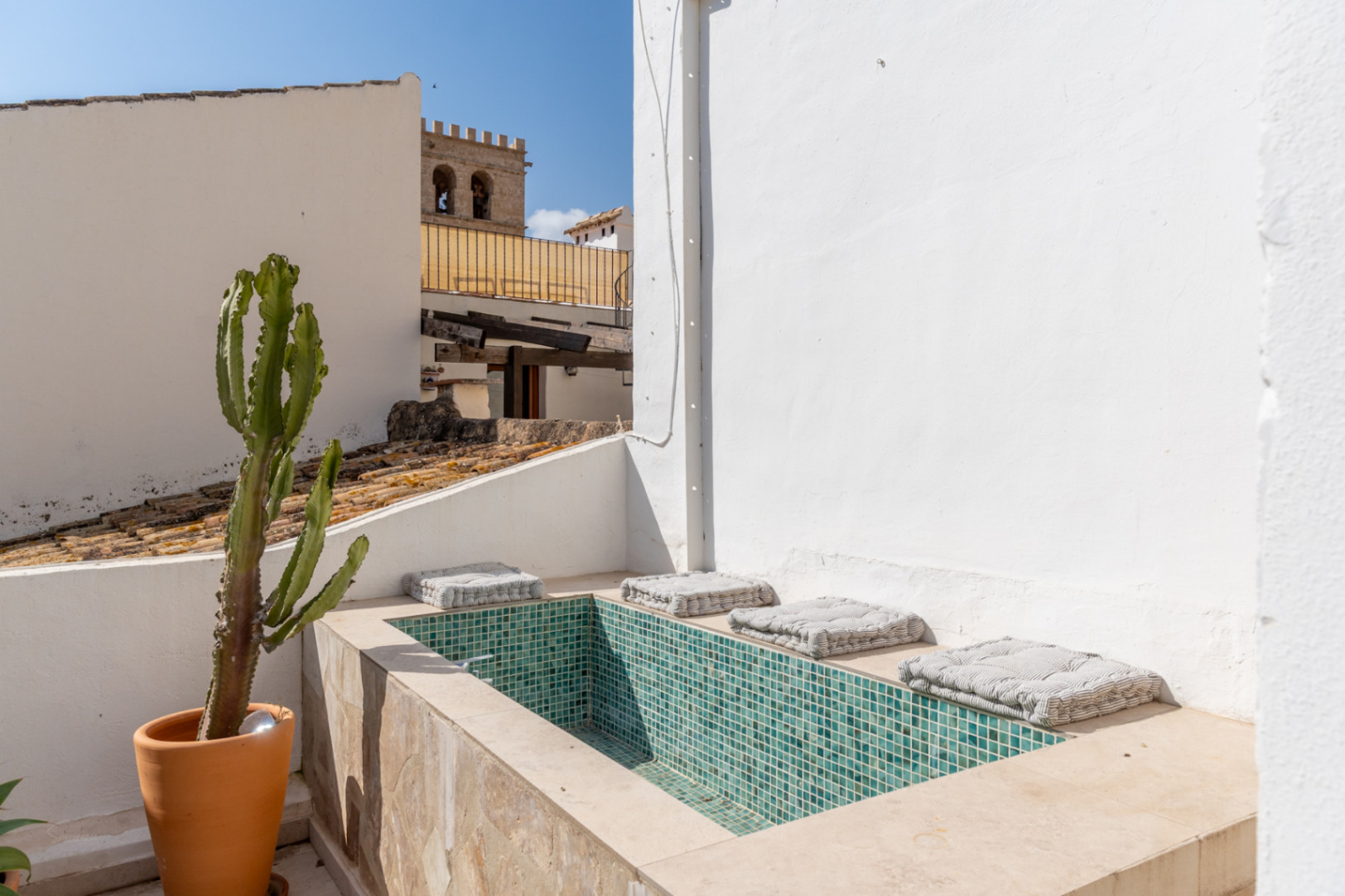 Détail de la terrasse avec jacuzzi en mosaïque turquoise et cactus en pot, donnant sur la vieille ville.