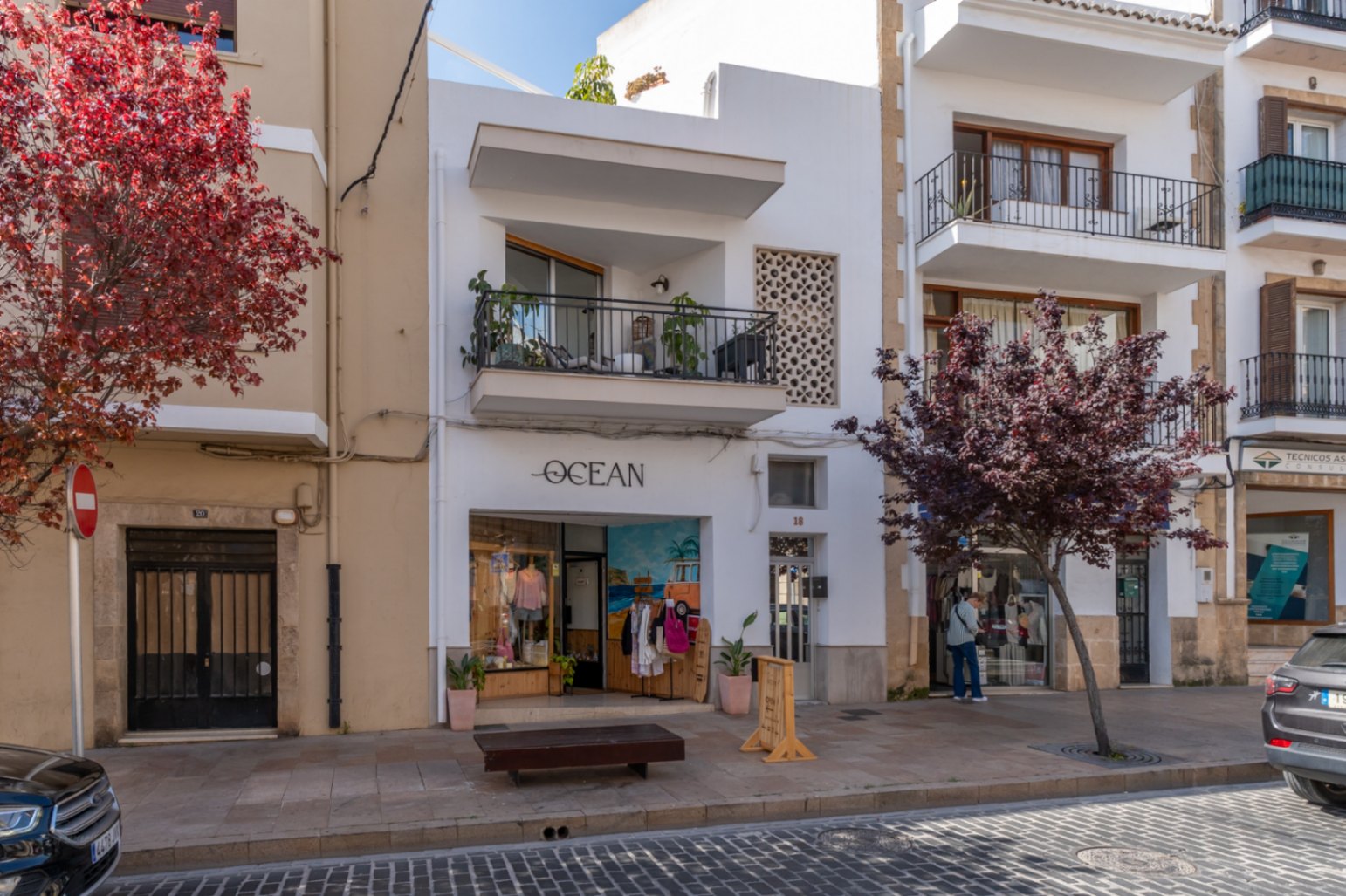 Façade rénovée d'un immeuble d'appartements dans la vieille ville, avec balcon et boutique au rez-de-chaussée.