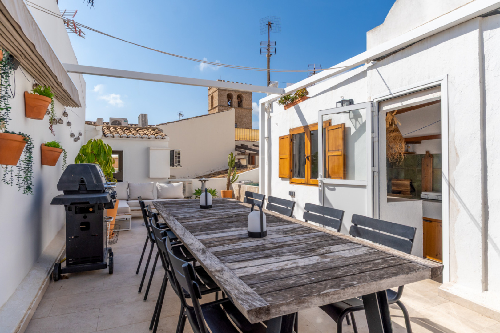 Terrasse avec table en bois rustique, barbecue et vue sur la vieille ville de Jávea.