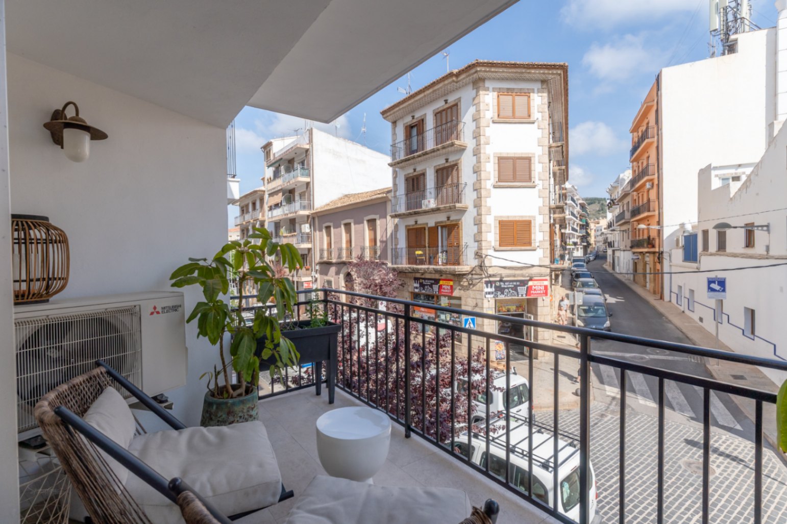 Terrasse avec vue sur la rue dans le centre historique de Jávea, avec mobilier d'extérieur et plantes ornementales.