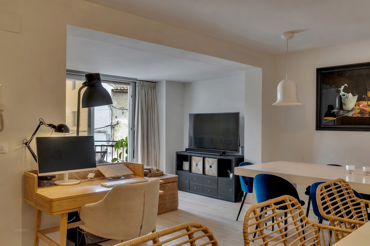 Vue du salon-salle à manger avec bureau en bois clair et accès au balcon à Jávea.