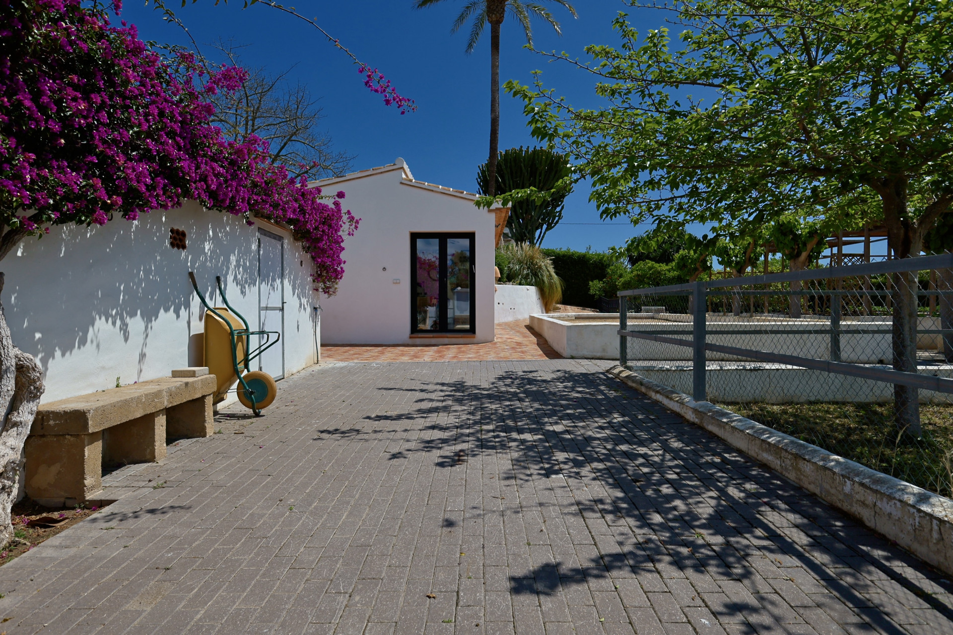 Entrée de la villa avec bougainvilliers et banc en pierre.
